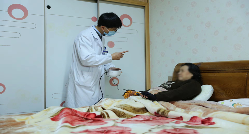 图为康复医生上门为残疾人进行手部运动康复